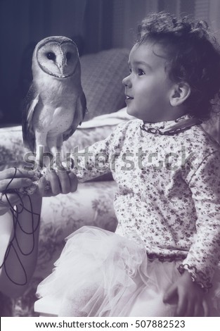 Cute little girl with little barn owl . Vintage style monochrome picture.