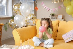 Cute Little Girl Blowing Balloons With Gifts And Decorations For Birthday At Home