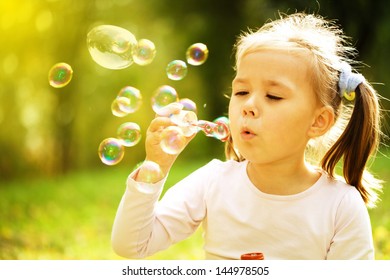 Cute kleine Mädchen weht eine Seifenblase