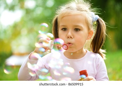 Cute little girl is blowing a soap bubbles