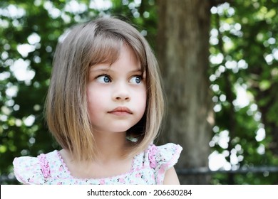 Cute little girl with bobbed hair cut looking away from camera. Extreme shallow depth of field.