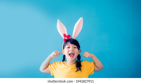 Cute Little Girl With Bunny Ears On Color Background.Strong Superhero Child.kid With Muscles, Milk, Calcium.Kid Girl Power In Easter Day.Asian Child Kid Girl Background.Health Care, Immune System.