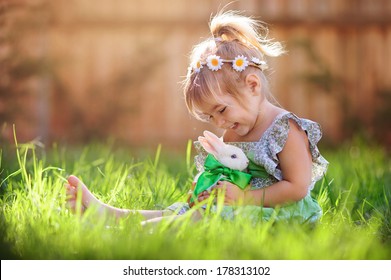 Cute little girl with a bunny rabbit has a easter at green grass background - Powered by Shutterstock