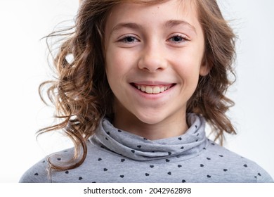 Cute little girl with a charismatic grin isolated on white in a close up cropped head shot as she smiles into the camera