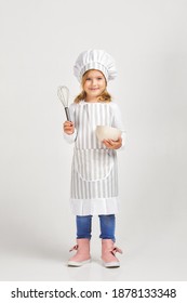 Cute Little Girl In Chef Hat And Apron With Bowl And Whisk. Child Dreams Of Becoming A Chef