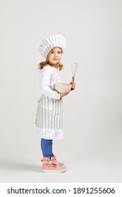 linda niñita con sombrero de chef y delantal con tazón y whisky. sueños infantiles de convertirse en chef