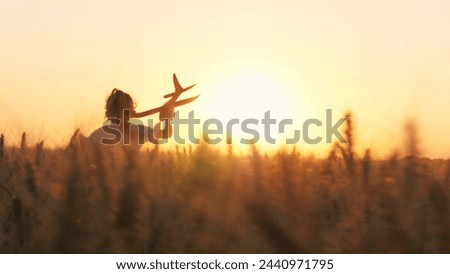 Cute little girl child running with plane toy playing at sunset sunrise wheat field happy childhood back view. Adorable female kid flying aircraft plaything pilot imagination fantasy enjoy freedom