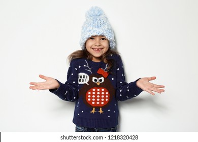 Cute Little Girl In Christmas Sweater And Knitted Hat On White Background