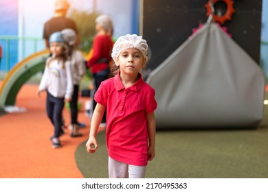 Cute little girl climber dressed protective hat before dress up helmet standing in climber centre amusement park for children. Caucasian female climber 5 years