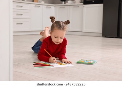 Cute little girl coloring drawing on warm floor in kitchen. Heating system - Powered by Shutterstock