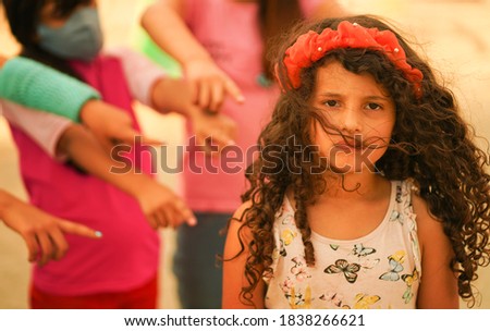 Cute little girl with curly hair being bullied and defending herself against some girls at school

             