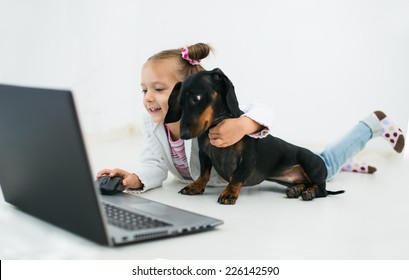 Cute Little Girl  And Dachshund Use Laptop