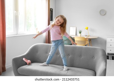 Cute Little Girl Dancing On Sofa At Home