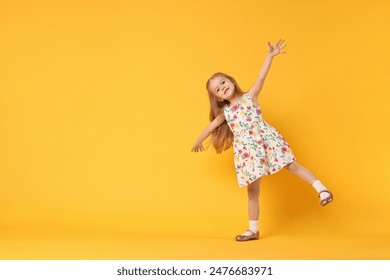 Cute little girl dancing on orange background, space for text - Powered by Shutterstock