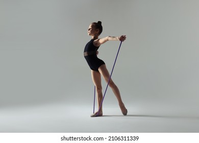 Cute Little Girl Doing Gymnastic Exercise With Rope On White Background