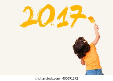 Cute little girl drawing new year 2017 with painting brush on wall background