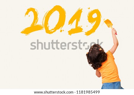 Cute little girl drawing new year 2019 with painting brush on wall background