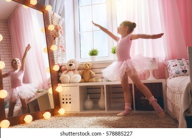 Cute Little Girl Dreams Of Becoming A Ballerina. Child In A Pink Tutu Dancing In A Kids Room.