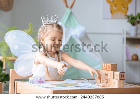 Cute little girl dressed as fairy sitting at home
