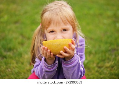 Cute Little Girl Eating Cantaloupe On The Grass