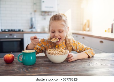 cute little girl eating cereal with the milk at home