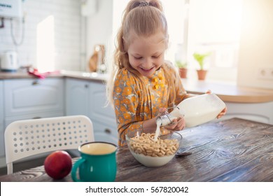 süßes kleines Mädchen, das zu Hause mit der Milch Müsli isst
