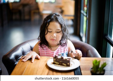 Cute Little Girl Eating Chocolate Cake With Bitter Taste. Facial Expressions Are Not Happy.