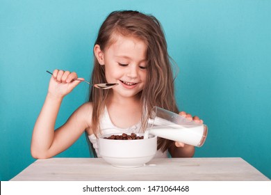 Cute Little Girl Eating Chocolate Cereal With Milk For Breakfast