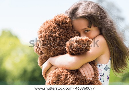 Cute little girl embracing her new teddy bear and looking at camera. Portrait of lovely female child with her peluche outdoor. Little girl playing with her doll.