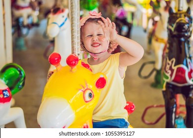 Cute little girl enjoying in funfair and riding on colorful carousel house