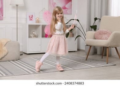 Cute little girl in fairy costume with pink wings and magic wand at home - Powered by Shutterstock