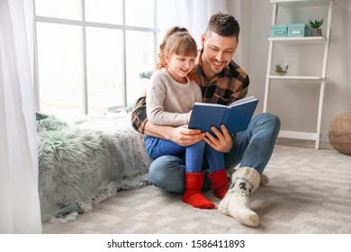 Cute little girl with father reading book at home - Powered by Shutterstock