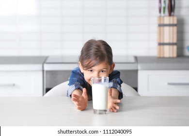 Cô bé dễ thương với ly sữa tại bàn trong nhà bếp