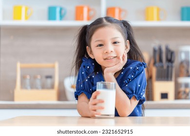 Cute little girl with glass of milk at table in kitchen, Happy child girl drinks milk - Powered by Shutterstock