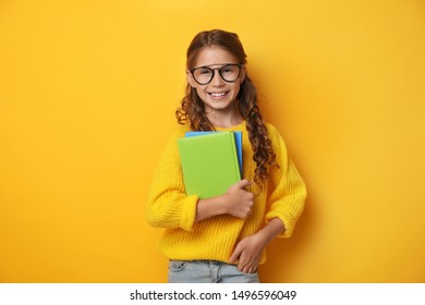 Cute Little Girl With Glasses And Books On Yellow Background. Reading Concept