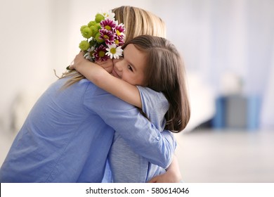 Cute little girl greeting her mother at home. Mother's day concept - Shutterstock ID 580614046