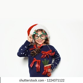 Cute Little Girl In Handmade Christmas Sweater And Hat With Party Glasses On White Background