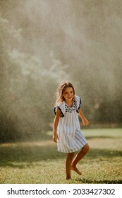 Cute Little Girl Having Fun With Water Under Irrigation Sprinkler