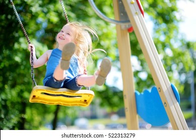 Cute little girl having fun on a playground outdoors in summer