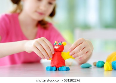 Cute little girl having fun with colorful modeling clay at a daycare. Creative kid molding at home. Child play with plasticine or dough.  - Powered by Shutterstock