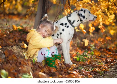 A cute little girl and her dalmatian outdoor during autumn