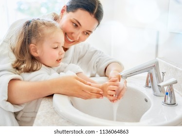 Cute little girl and her mother are washing hands under running water. - Shutterstock ID 1136064863