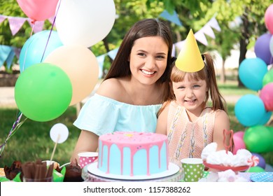Cute little girl with her mother at birthday party outdoors