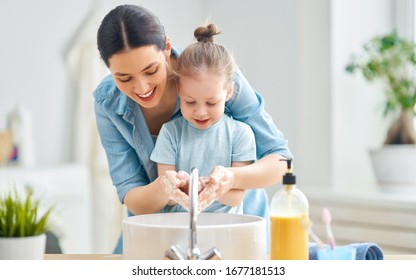 A cute little girl and her mother are washing their hands. Protection against infections and viruses.                               