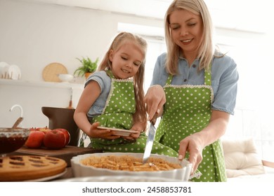 Cute little girl and her mother cutting prepared apple pie in kitchen - Powered by Shutterstock