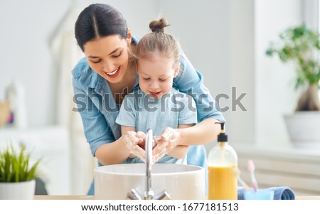 A cute little girl and her mother are washing their hands. Protection against infections and viruses.                               