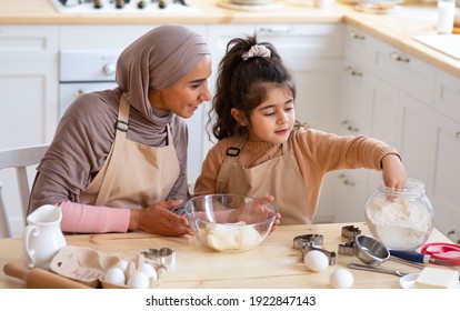 Cute Little Girl And Her Muslim Mom In Hijab Preparing Pastry For Cookies In Kitchen, Baking Together At Home. Islamic Lady With Small Daughter Enjoying Doing Homemade Pastry, Free Space