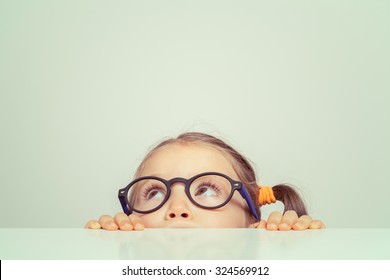 cute little girl hiding behind the table - Shutterstock ID 324569912