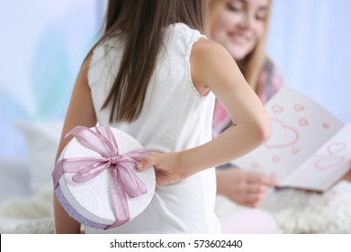 Cute Little Girl Hiding Present For Her Mother Behind Back, Close Up. Mother's Day Concept