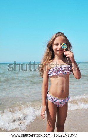Cute little girl holds a colorful candy in hand. Summertime concept.
